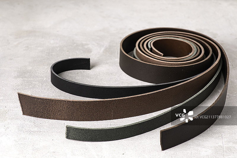 灰色背景上卷成一圈的皮革腰带图片素材