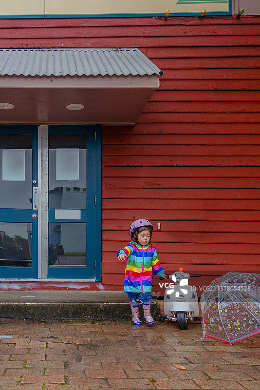 下雨天红木屋处的穿花式雨衣的小女孩图片素材