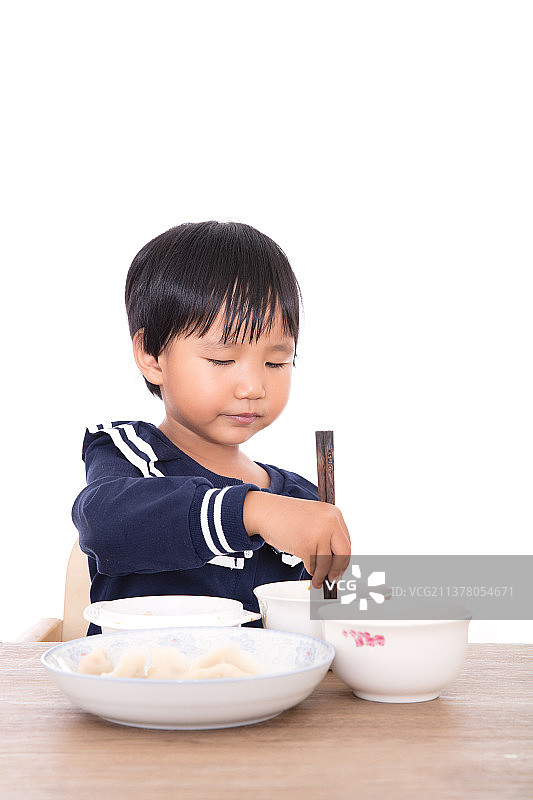 黄皮肤小姑娘在餐桌上仔细的吃饭图片素材