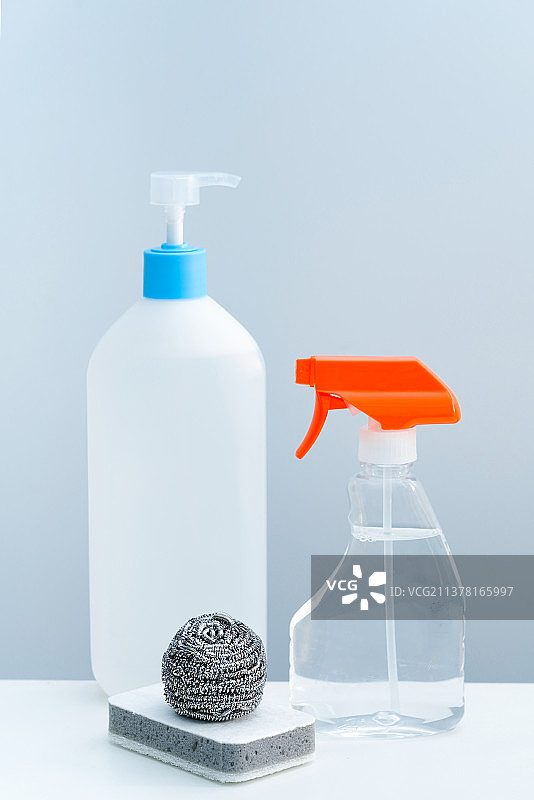 一瓶透明的清洁剂和清洁球放在白色桌面上图片素材