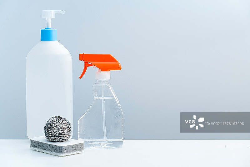 一瓶透明的清洁剂和清洁球放在白色桌面上图片素材