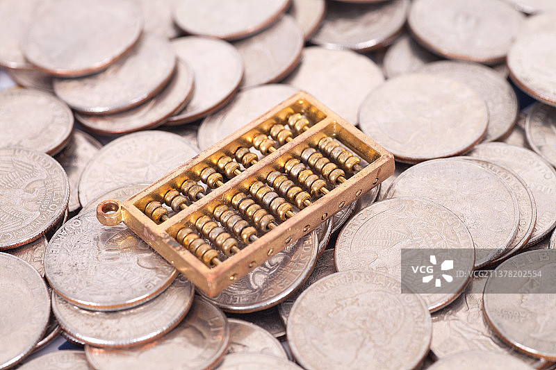 大量美元硬币上一个金色的算珠工具图片素材