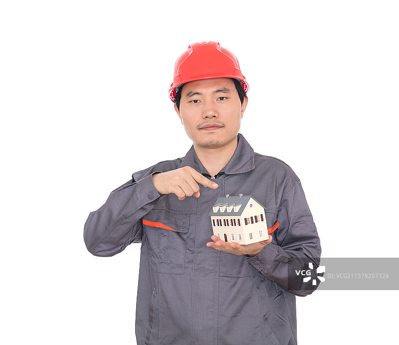 头戴红色安全帽的建筑师查看手中的小房子模型图片素材