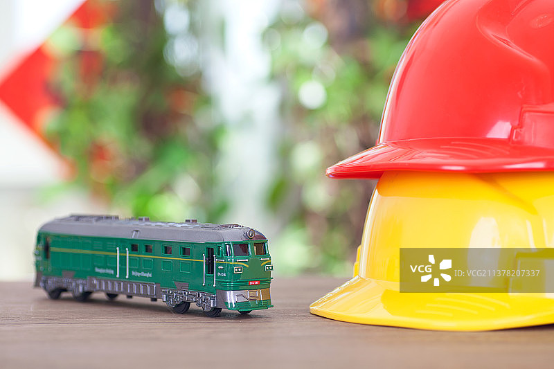 桌子上两顶安全帽和一辆绿皮火车模型图片素材