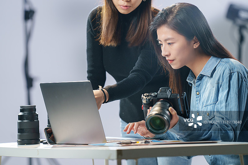 在工作室里讨论工作的青年女摄影师图片素材