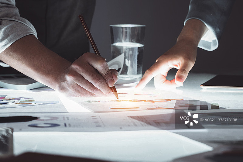 商务人士拿着铅笔指着报表分析研究图片素材