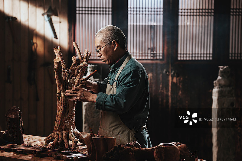 在树根上认真雕刻的工匠师图片素材