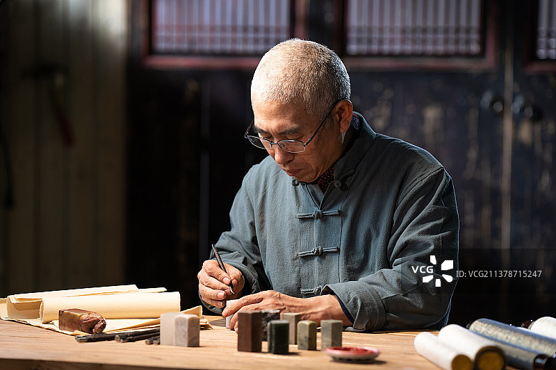 在工作室里认真雕刻印章的专家图片素材