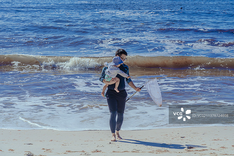 澳洲悉尼大白沙滩小男孩与爸爸一起捕捞鱼虾图片素材