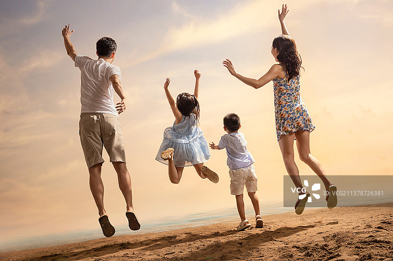 沙滩上跳跃的快乐四口之家背影图片素材