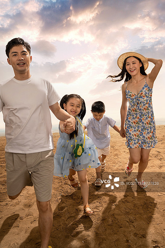 幸福的一家四口在沙滩上散步图片素材