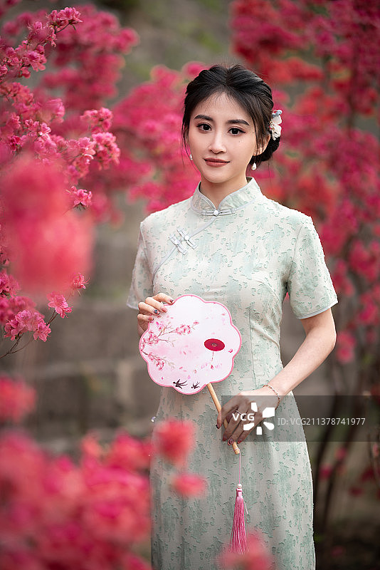 穿旗袍的女子站在花丛里图片素材