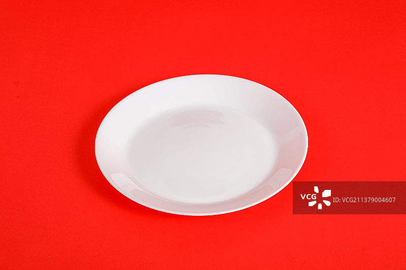 白色圆盘子孤立在红色背景上图片素材