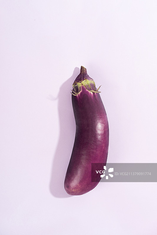 淡紫色背景上的一根新鲜茄子图片素材