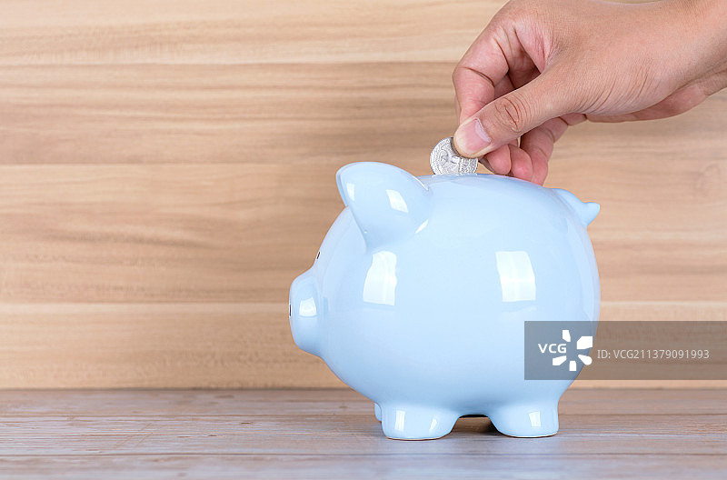 把硬币放入小猪存钱罐图片素材
