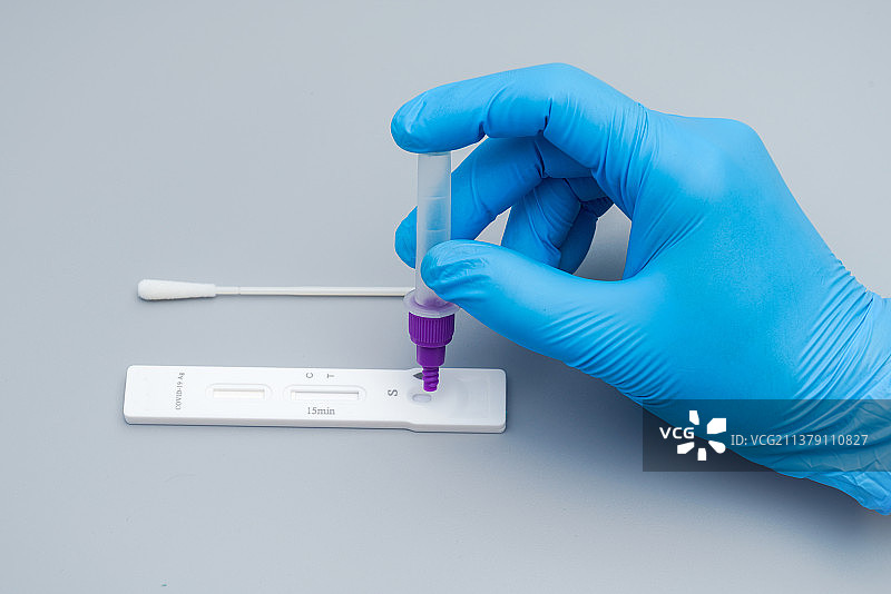 带着蓝色手套的手拿检测试剂瓶图片素材