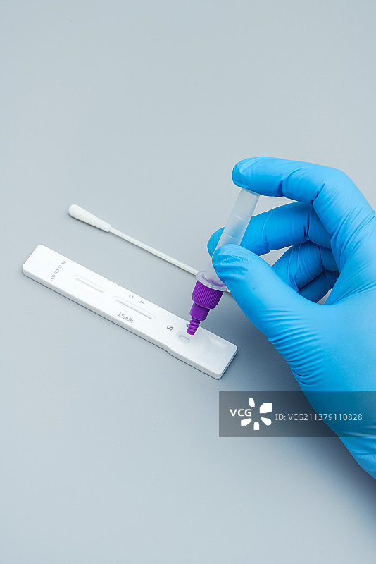 带着蓝色手套的手拿检测试剂瓶图片素材