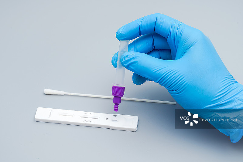 带着蓝色手套的手拿检测试剂瓶图片素材