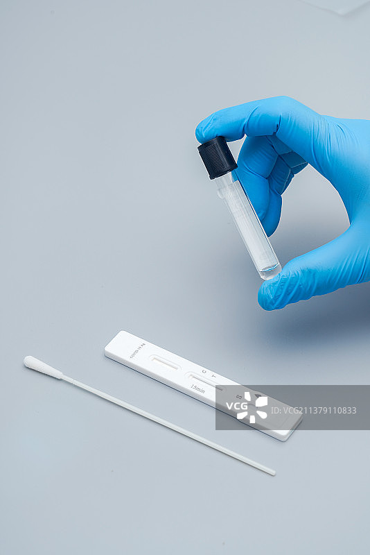 带着蓝色手套的手拿检测试剂瓶图片素材