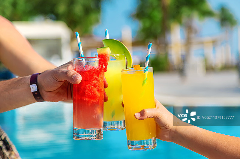 泳池边一家人手中的鸡尾酒图片素材