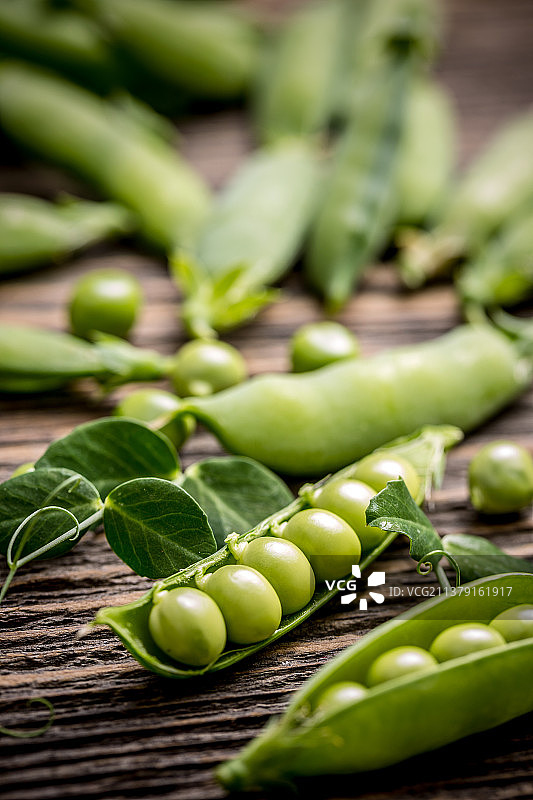 复古木质背景上的绿豌豆荚和豌豆图片素材