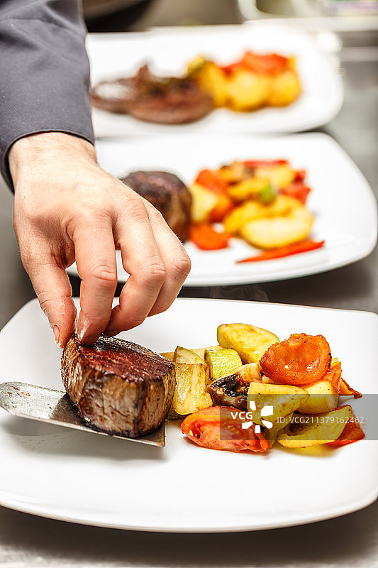 厨师在做晚餐，男子手中端着盘中的食物图片素材