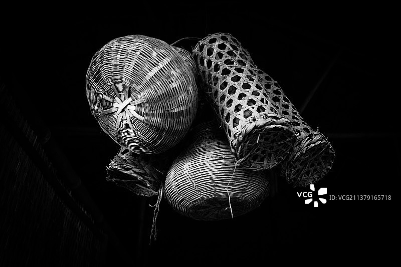 鱼篓，黑色背景下悬挂的柳条筐的低角度视图图片素材