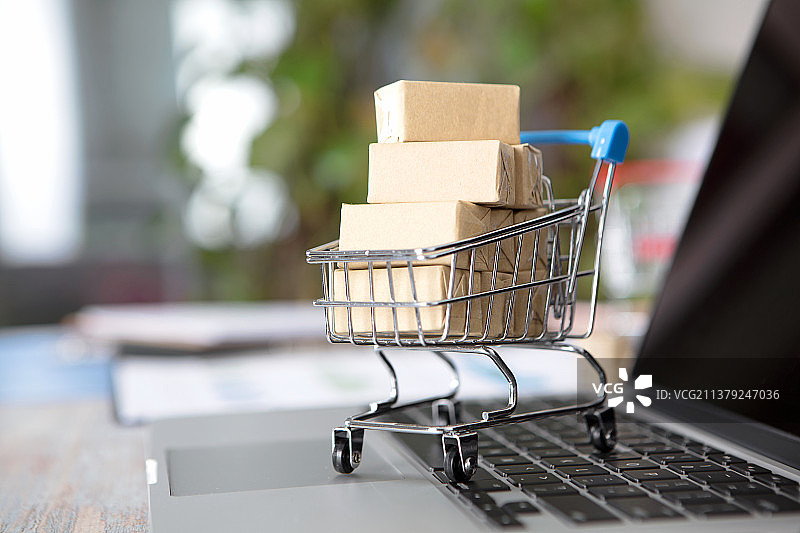 笔记本电脑键盘上满载货物的购物车图片素材