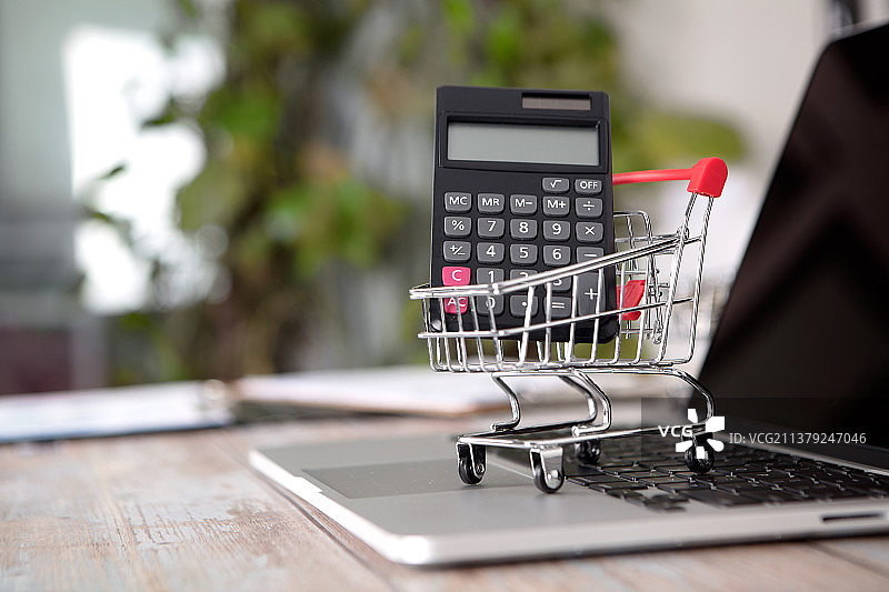 笔记本电脑键盘上载着计算器的购物车图片素材
