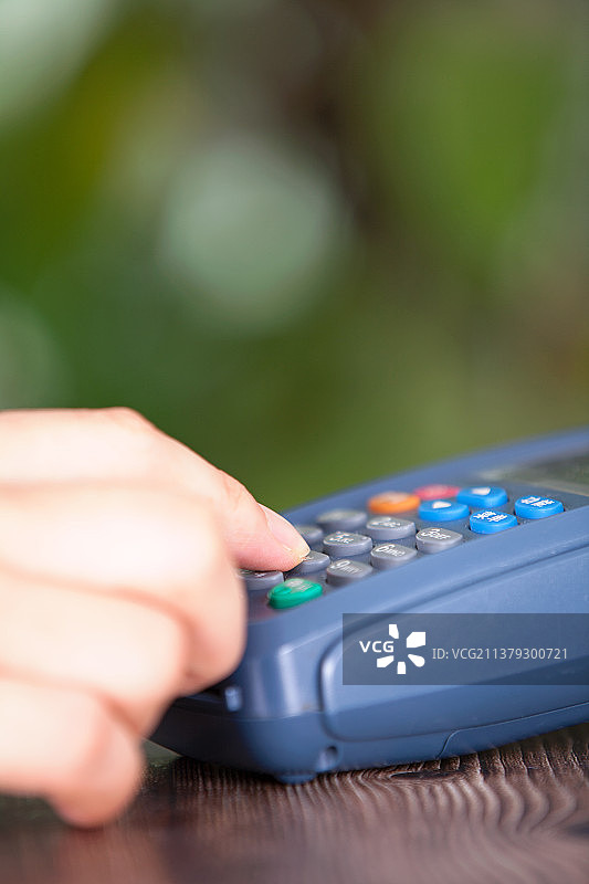 一只手正在pos机上输入收款金额图片素材