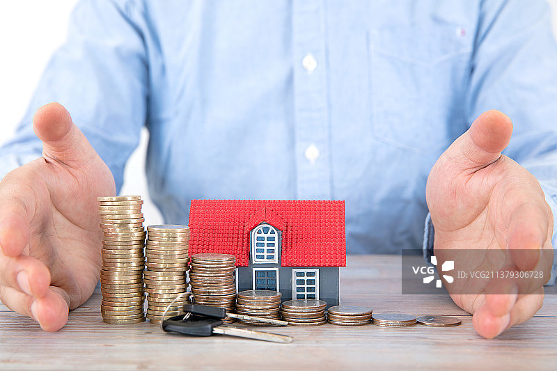 一双手呵护着一排硬币和小房子模型图片素材