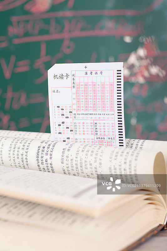 黑板前书页折成爱意心形和一张考试答题卡图片素材