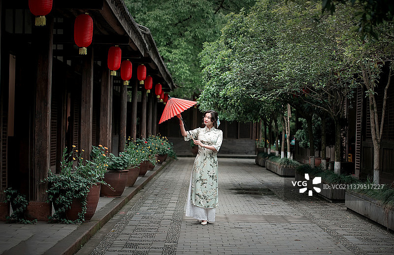 一个女人撑着一把红色油纸伞走在古镇的街道上图片素材