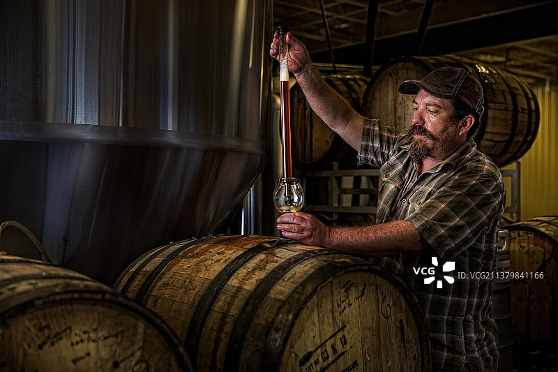 酿酒师用取样器从啤酒桶中取样图片素材