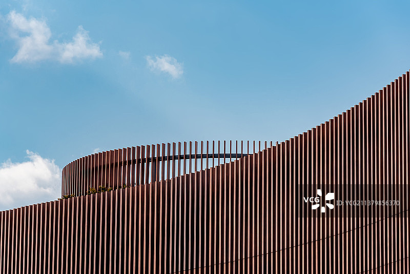 蓝天白云下奉贤博物馆金色金属规则的曲线形外墙被温暖的夕阳照亮图片素材