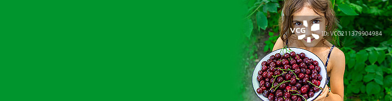 孩子在花园里吃樱桃，选择性聚焦图片素材