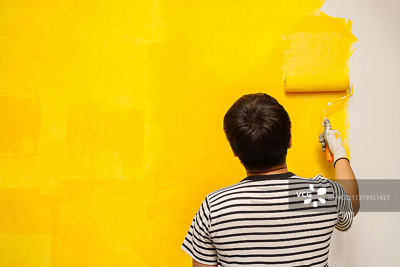油漆工正在将室内墙壁涂成黄色图片素材