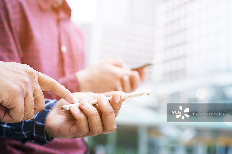 商人团队站立开会（男子使用手机的中段镜头）图片素材