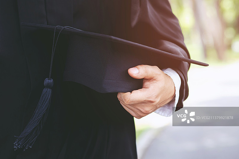 大学毕业生，手持毕业帽的男子图片素材