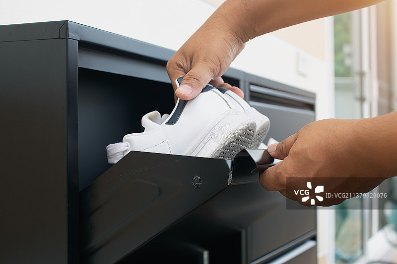 男人打开黑色钢制鞋柜存放她的鞋子图片素材