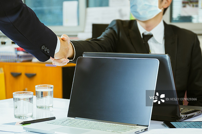 戴着防护口罩握手成功达成协议的泰国商人图片素材