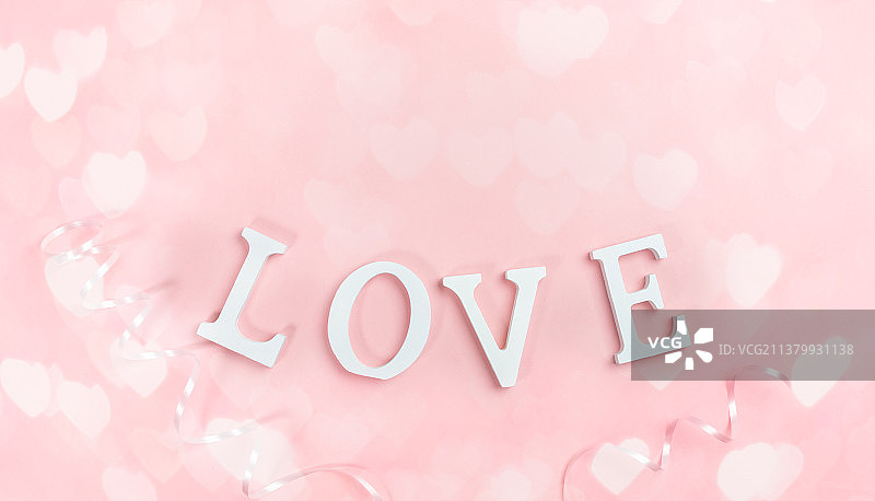 粉色背景上的白色“LOVE”字母，带有散景灯光心形图案图片素材