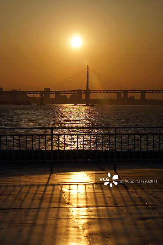 海湾大桥日落：日落时分河流上的悬索桥景观图片素材