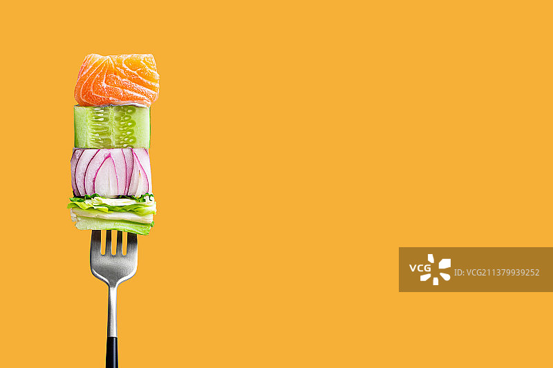 叉子叉着的美味鱼片，配黄瓜、洋葱和蔬菜图片素材