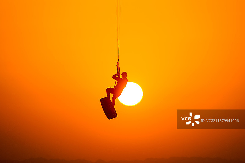 仰视悬挂在橙色天空下的照明设备图片素材