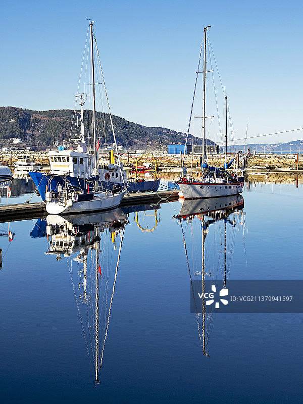 挪威特隆赫姆平静水面上的帆船倒影图片素材