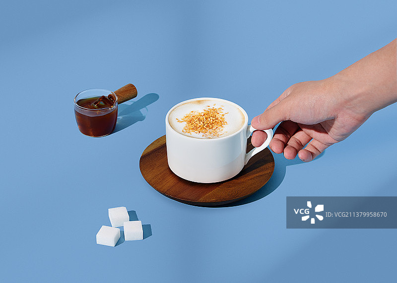 生椰拿铁咖啡在蓝色背景手拿杯子图片素材