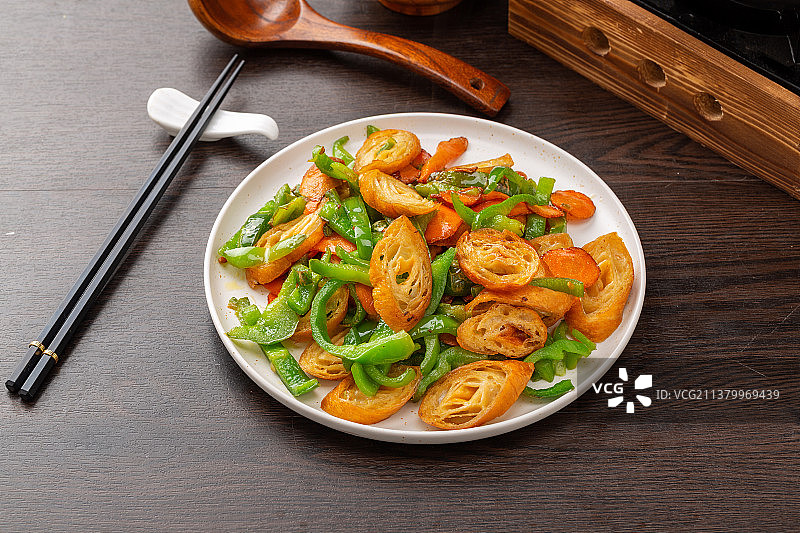 木桌面上盘子里的青椒炒面筋图片素材