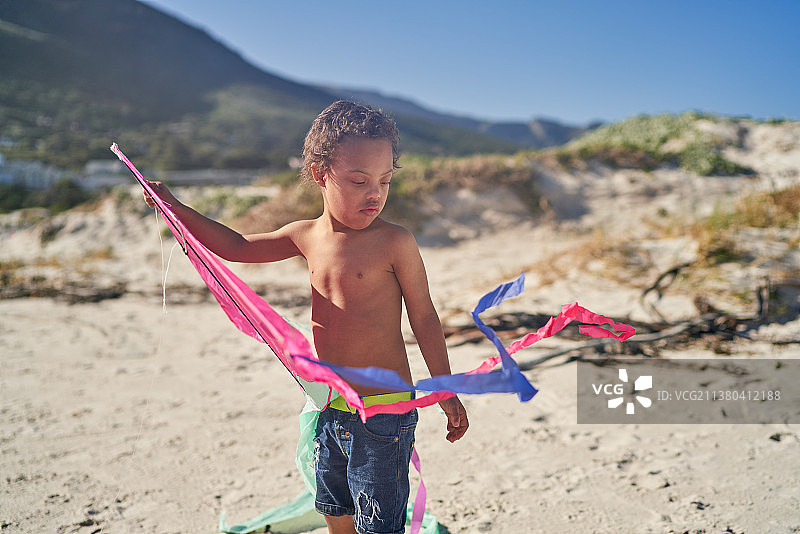 患有唐氏综合征的男孩在海滩上玩风筝图片素材