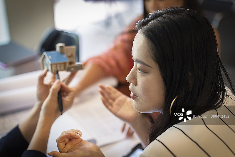 女建筑师在会议中与同事讨论房屋模型图片素材
